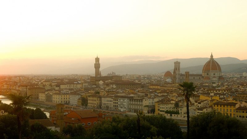 The photograph depicts a cityscape with a prominent cathedral and a river, set against a hazy sky.