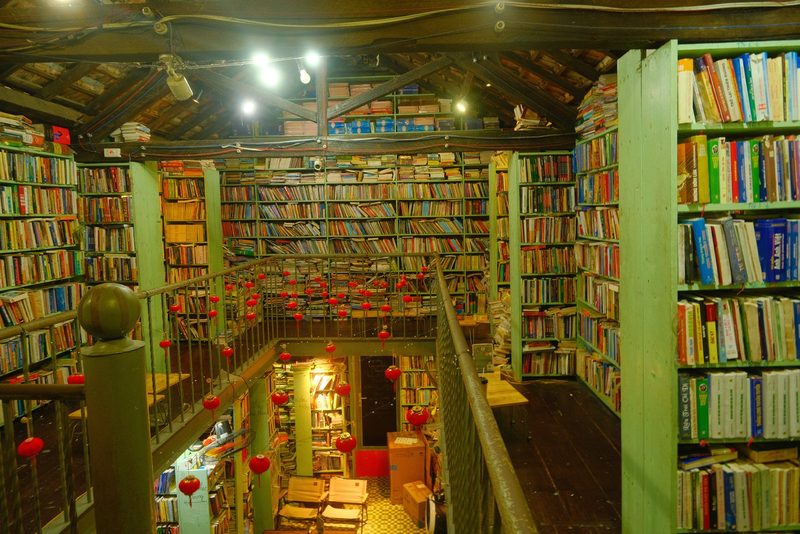 A large room with many books on shelves and a staircase with red lanterns.