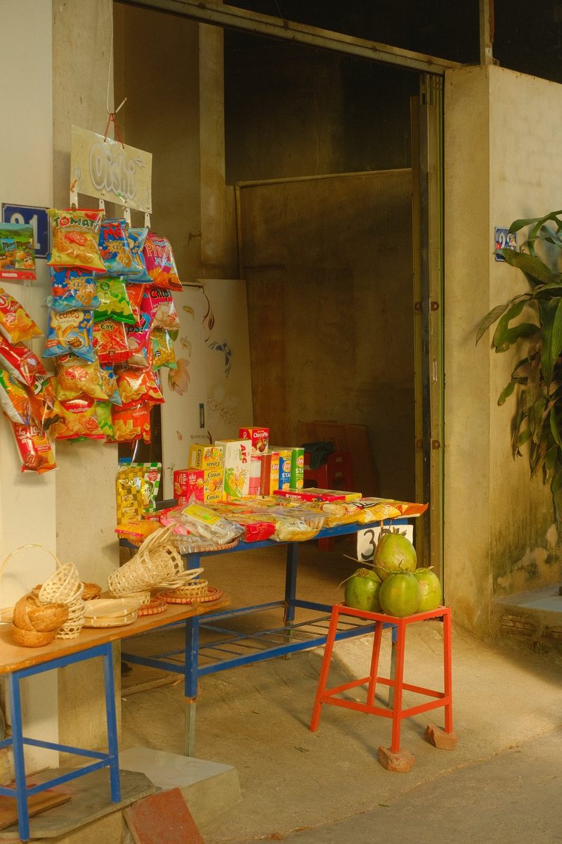 A small outdoor market stall with colorful snacks and woven baskets on display.