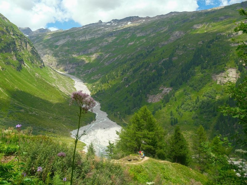 A valley with a river running through it, surrounded by mountains and greenery.
