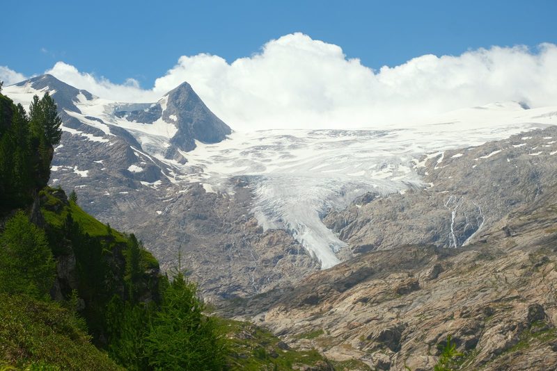Snow-capped mountain peaks and glaciers in a rocky landscape under a blue sky with clouds.
