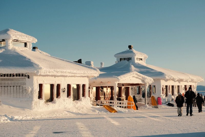A large building covered in snow, with a few people standing outside.