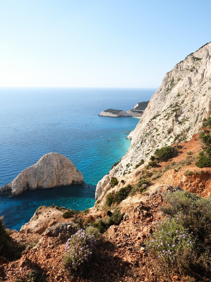 A rugged coastline with a steep cliff face, featuring a rocky shoreline and a clear blue sea.