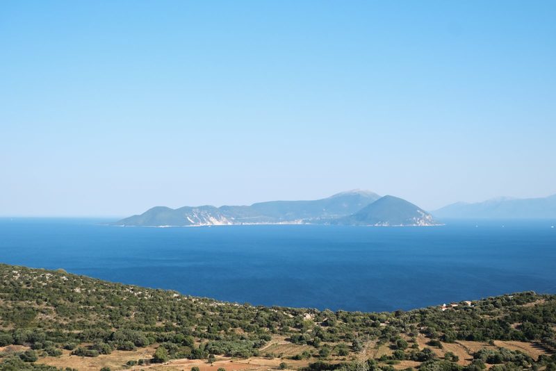 A large body of water, possibly an ocean or sea, with a mountainous coastline and a clear blue sky.