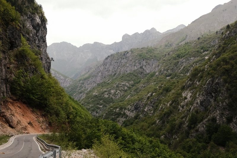 A winding road through a mountainous region with steep cliffs and lush greenery.