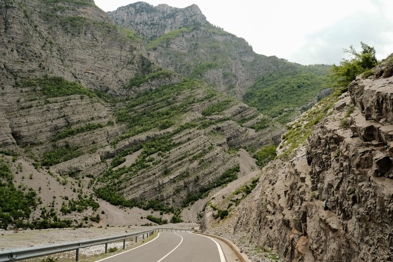A winding road through a mountainous region with steep cliffs and rocky terrain.