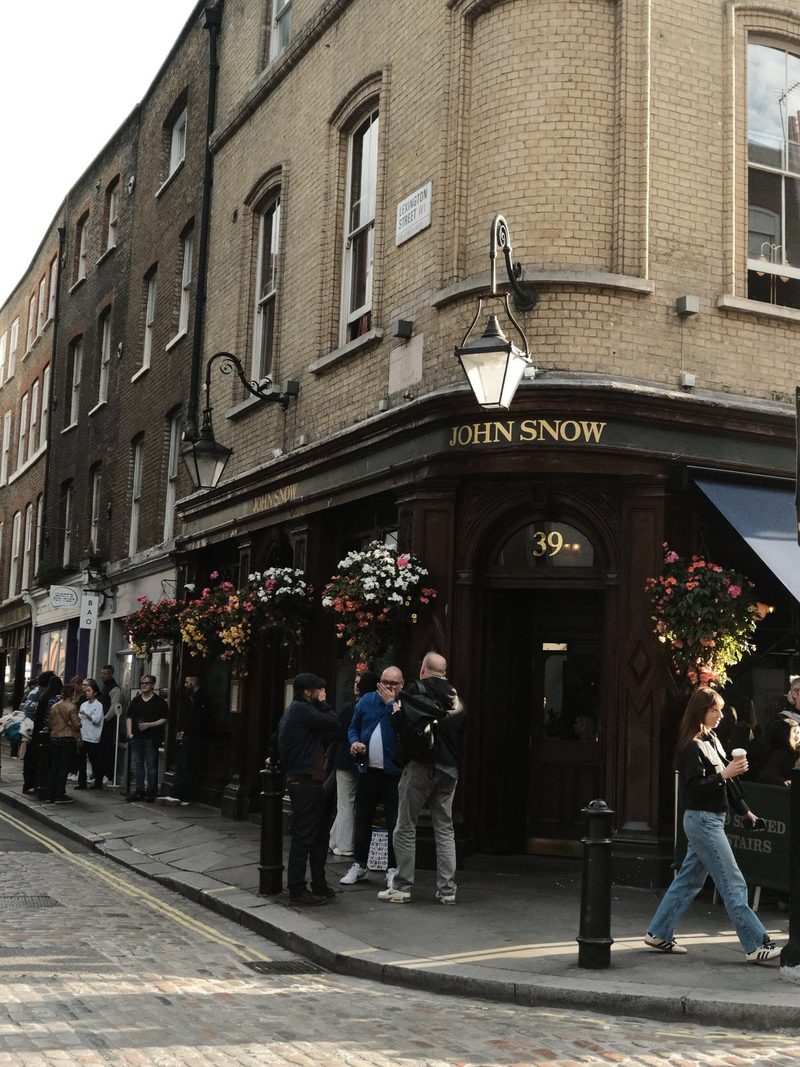A street corner in London with a pub and people standing outside.