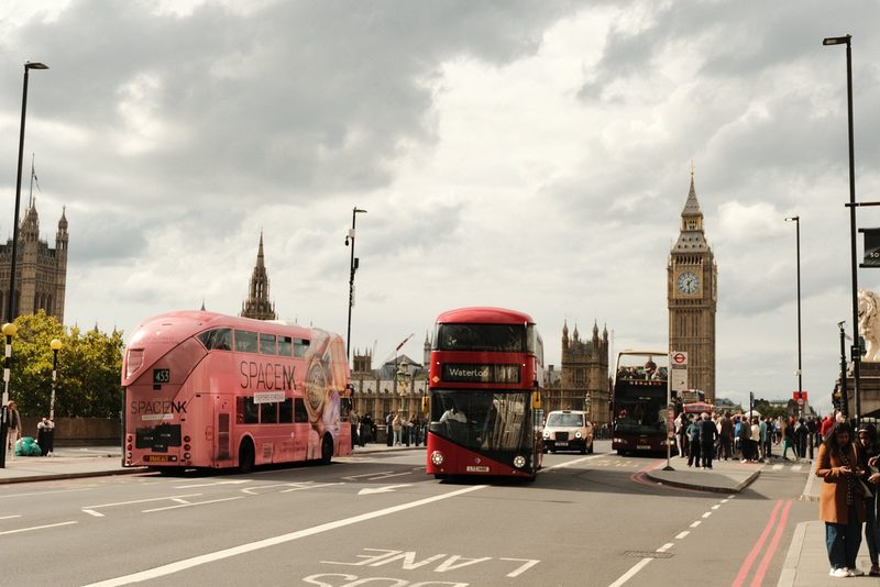 A busy street in London with iconic landmarks and double-decker buses.