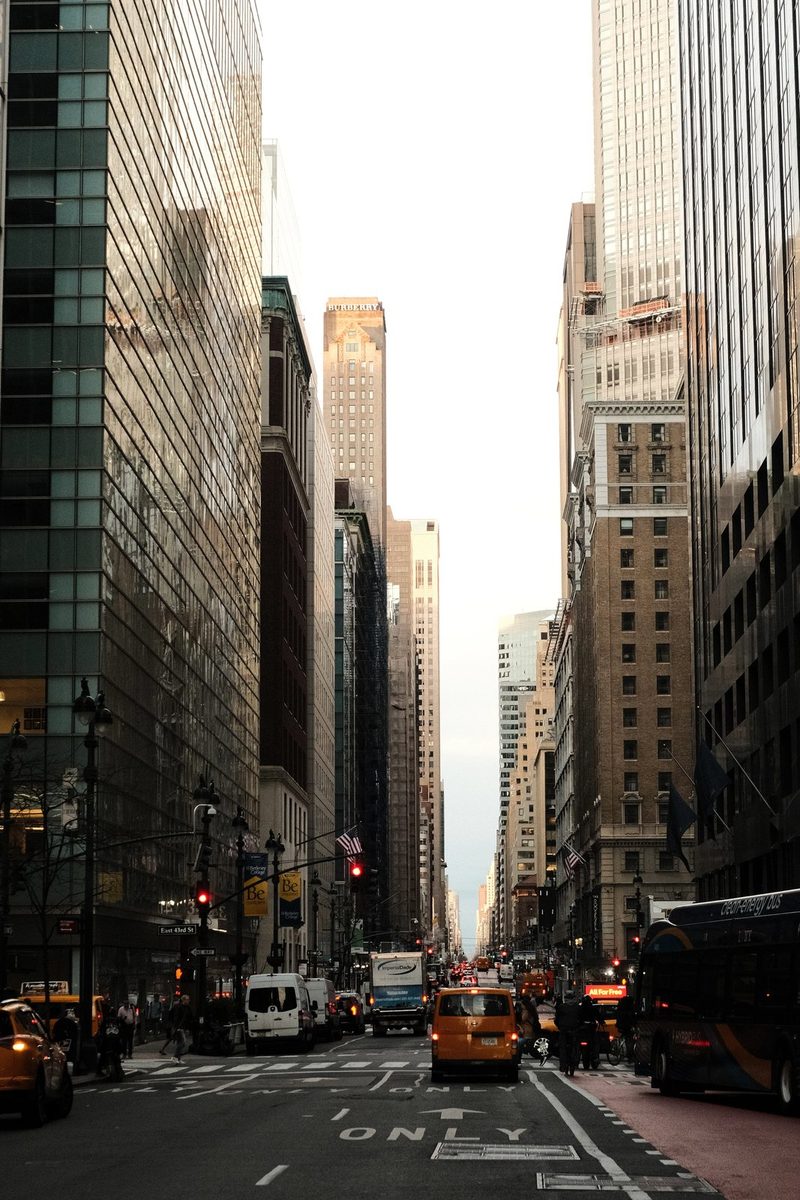 A city street with tall buildings and traffic on a cloudy day.