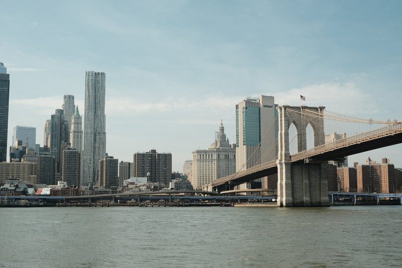 A city skyline with a bridge over a body of water.