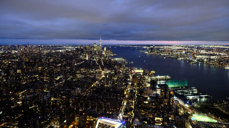 A cityscape with a large body of water and a cloudy sky.