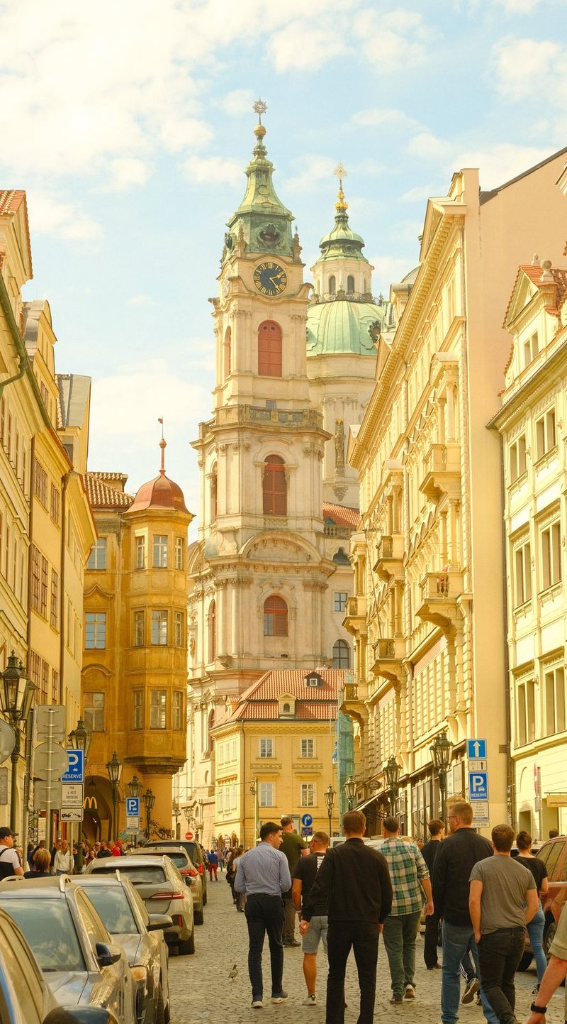A street in Prague, Czech Republic, lined with historic buildings and a prominent church.