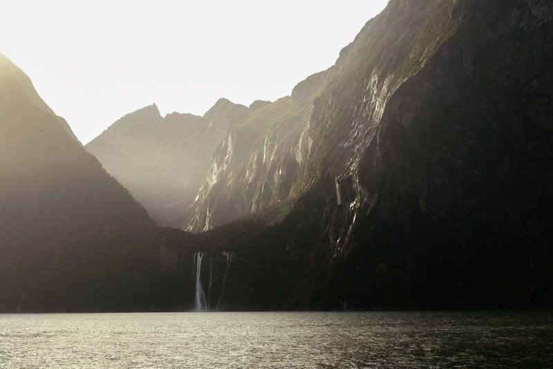 A serene mountainous landscape with a waterfall and lake.