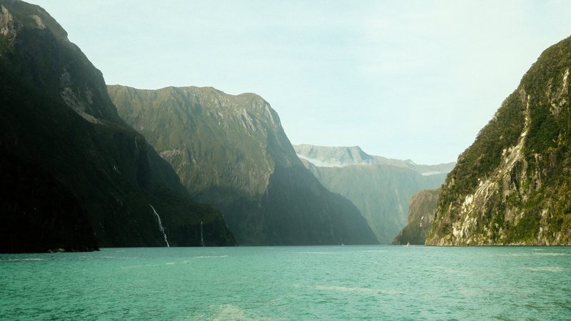A serene mountainous landscape with a large body of water in the foreground.