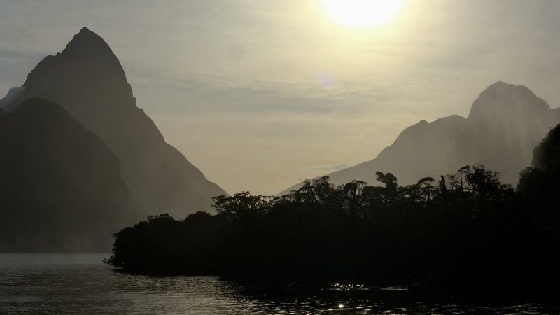 A serene lake surrounded by mountains and trees, with a boat in the water.