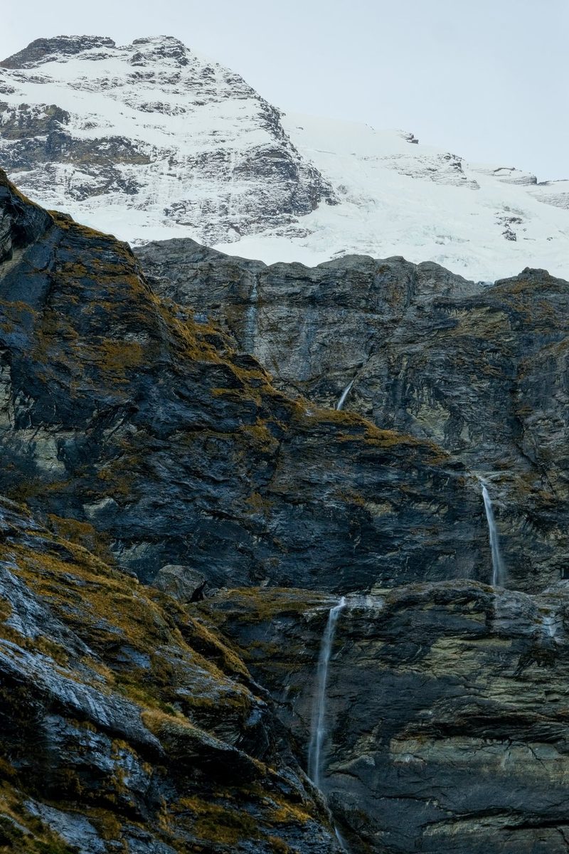 A snow-capped mountain with a waterfall cascading down its rocky face.