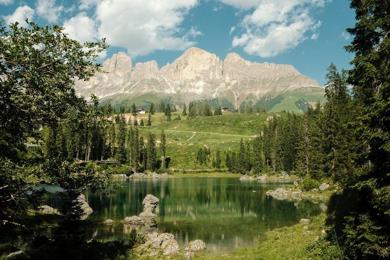 A serene landscape featuring a tranquil lake, surrounded by lush greenery and majestic mountains in the distance.