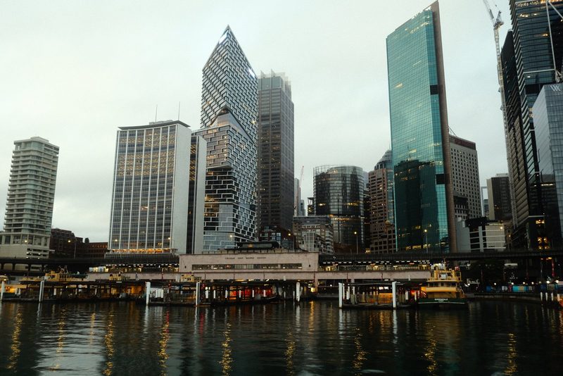 A city skyline with a large body of water in the foreground, featuring a mix of tall buildings and a dock or pier.