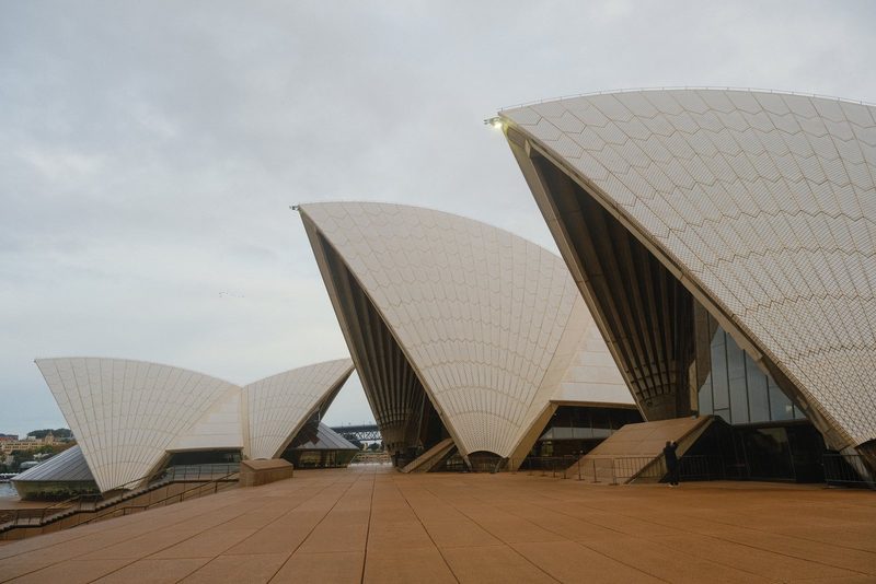 The photograph features a row of large, white, curved structures with a series of lines and shapes on their surfaces.