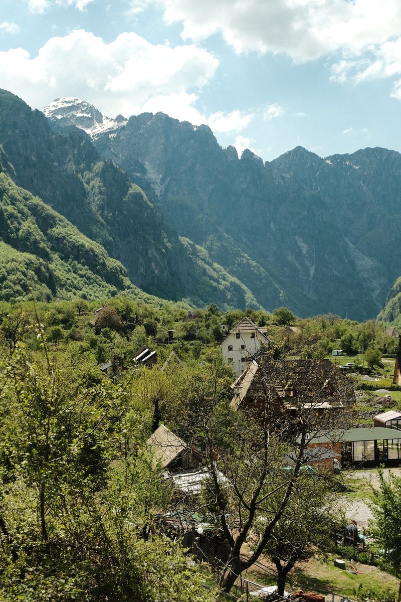 A mountainous landscape with a village in the foreground and a blue sky with clouds in the background.