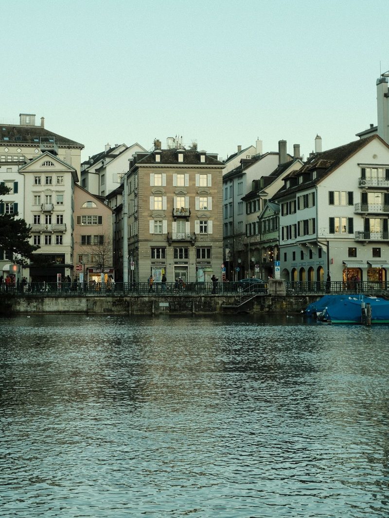 A row of multi-story buildings with a bridge over a body of water in front of them.